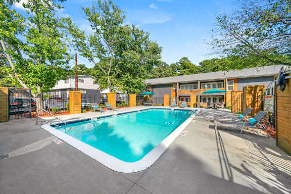 A large outdoor swimming pool surrounded by trees and a building.