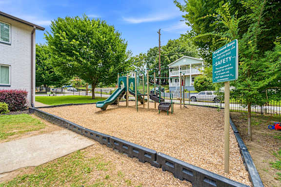 A playground with a green slide and a safety sign.