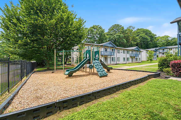 A playground with a green slide and a sandbox.