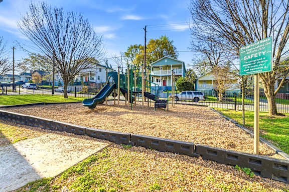 A playground with a green slide and a safety sign.