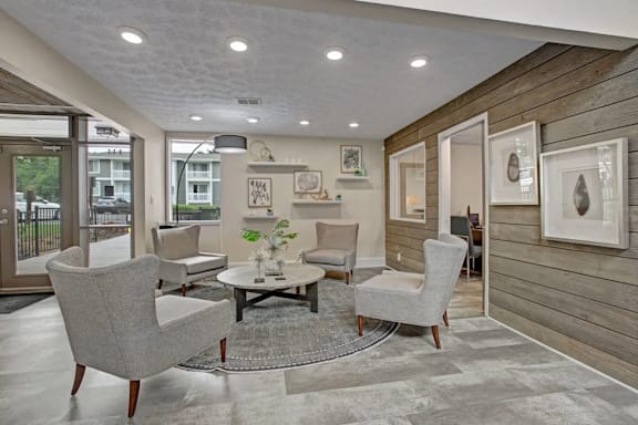 A modern living room with grey chairs and a wooden wall.