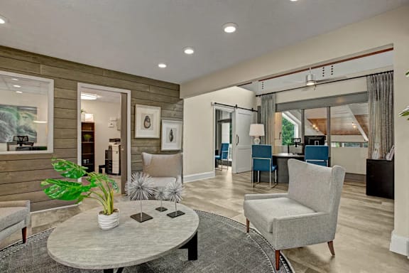 A living room with a grey sofa and a round table with a plant on it.