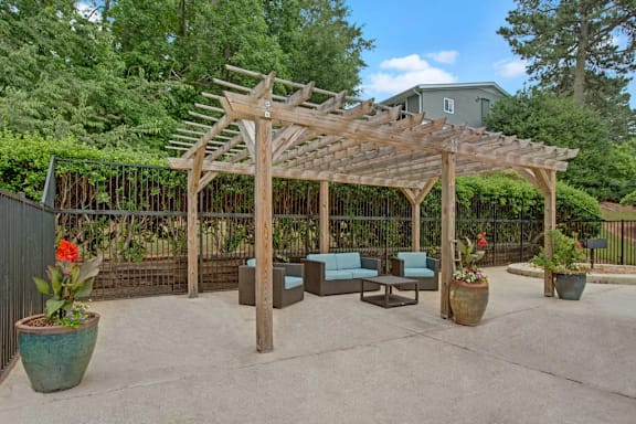 A wooden pergola with a bench and potted plants.