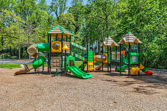 A playground with a green slide and a yellow and green play structure.