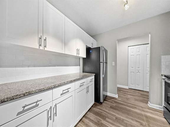 A kitchen with white cabinets and a black fridge.