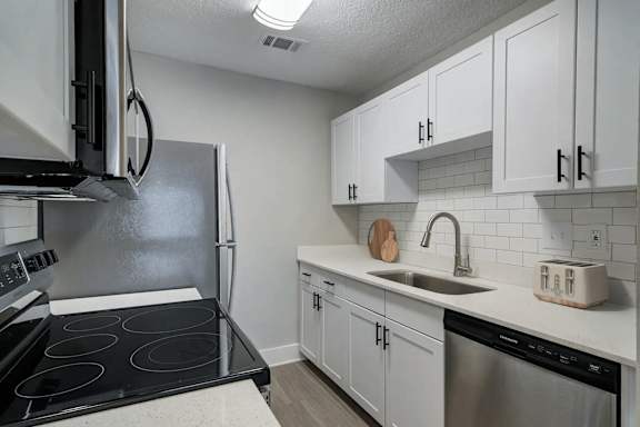 A kitchen with white cabinets and a black stove top.