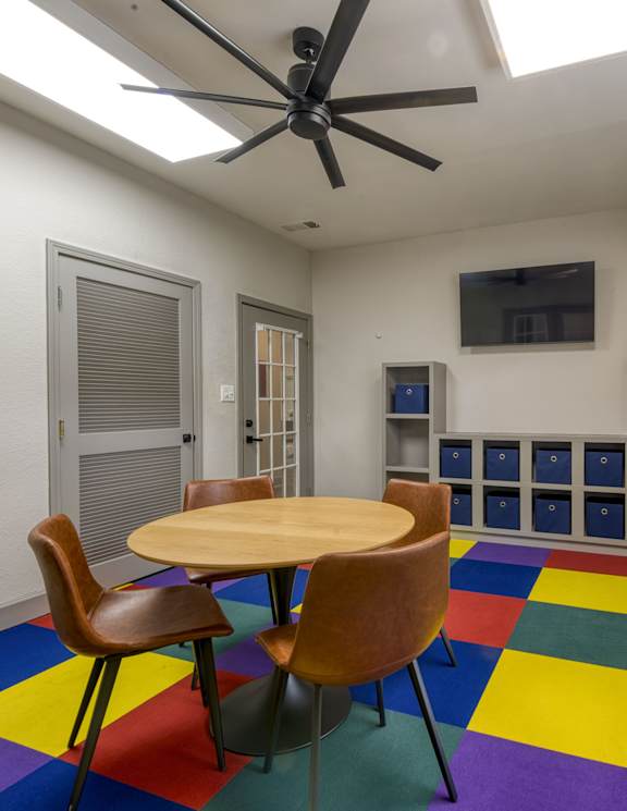 A room with a table and chairs and a ceiling fan.