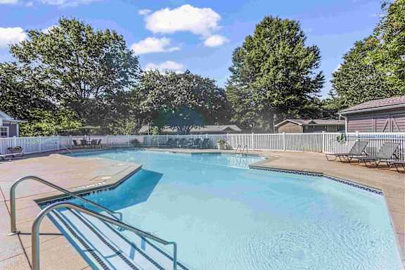 A large swimming pool surrounded by a fence and trees.