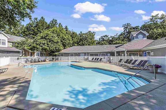 A large swimming pool surrounded by lounge chairs and trees.