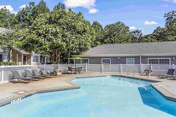 A pool surrounded by a fence and trees.