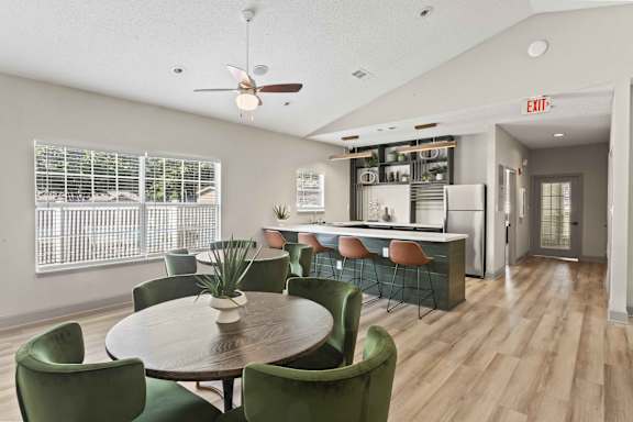 A dining room with a round table surrounded by green chairs.