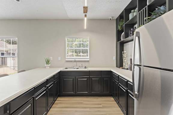 A kitchen with black cabinets and a white refrigerator.