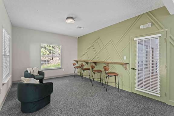 A room with a green couch, chairs, and a window with blinds.