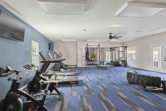 A gym with a variety of exercise equipment including treadmills, stationary bikes, and weight machines.