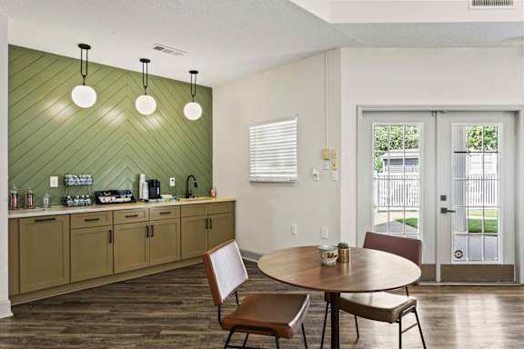 A kitchen with a green wall and a table with chairs.