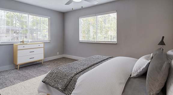 A bedroom with a bed, dresser, and window.