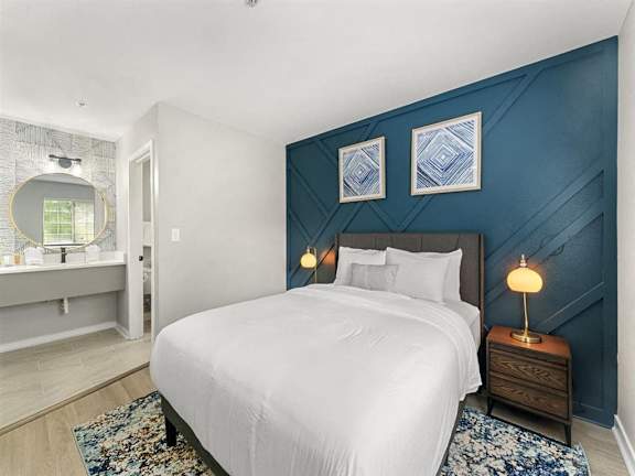 A bedroom with a white bed and a blue accent wall.