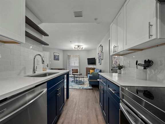 A modern kitchen with dark blue cabinets and stainless steel appliances.