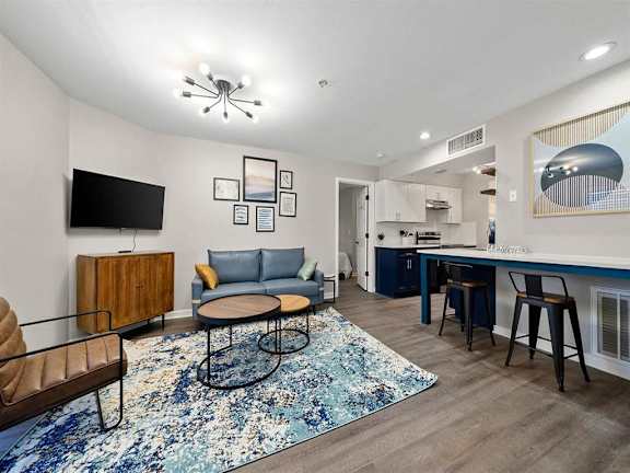 A living room with a blue rug and a wooden cabinet.