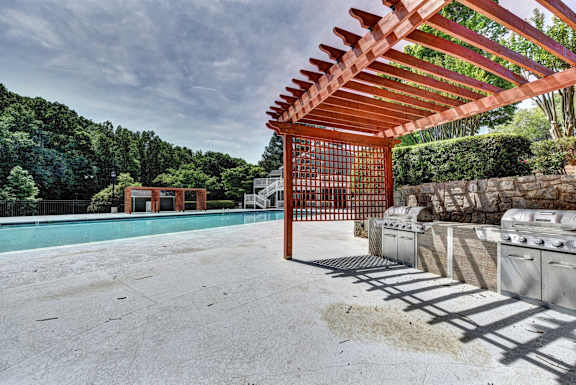 A red pergola is over a concrete patio.