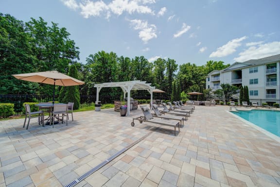 outdoor kitchen and grilling area with poolside seating