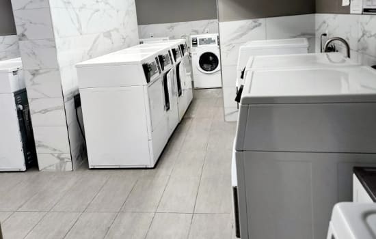 A row of white washing machines in a laundry room.