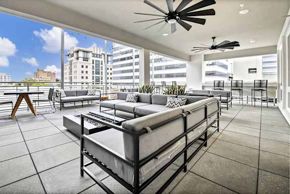 A modern outdoor patio with a large couch and a ceiling fan. at The Palms 1101, Columbia, SC