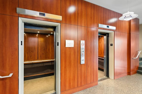 Two elevators in a wood panelled hall.