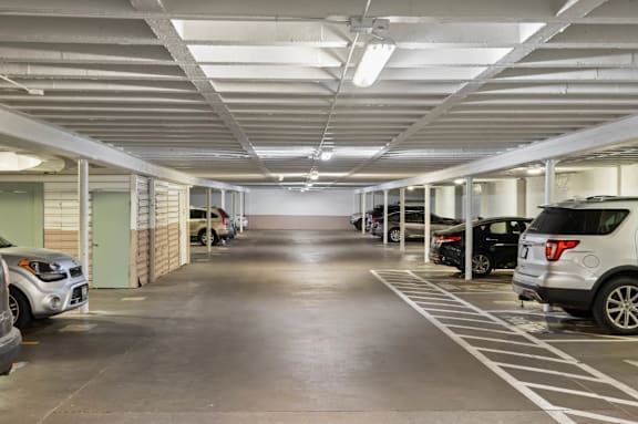 A parking garage with cars parked on both sides of the aisle.