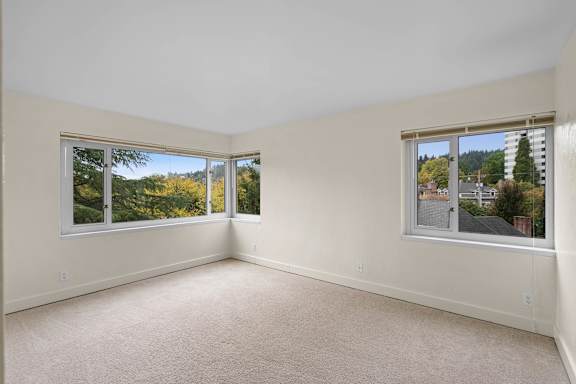 a living room with three windows and a carpeted floor