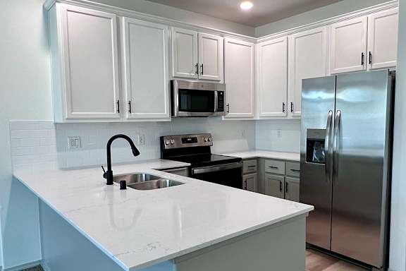 A kitchen with white cabinets and a stainless steel refrigerator. at Madison Sierra Sun, Puyallup