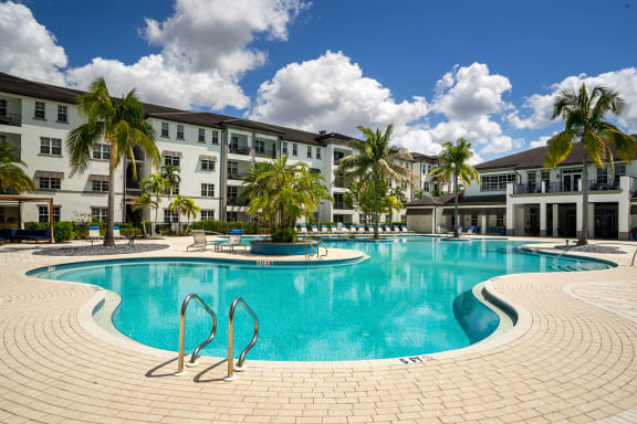 a swimming pool at an apartment complex with palm trees