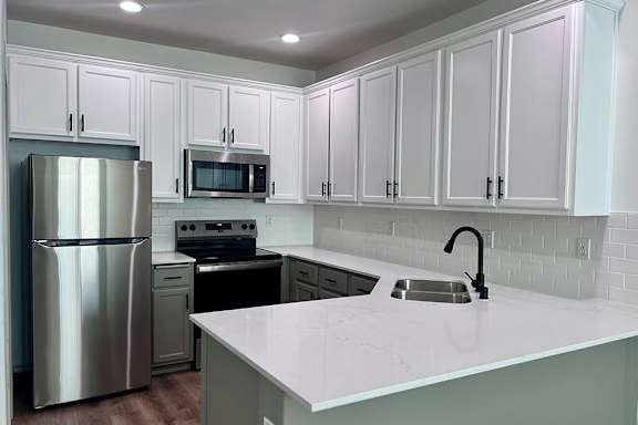 A kitchen with white cabinets and a stainless steel refrigerator. at Madison Sierra Sun, Washington, 98374