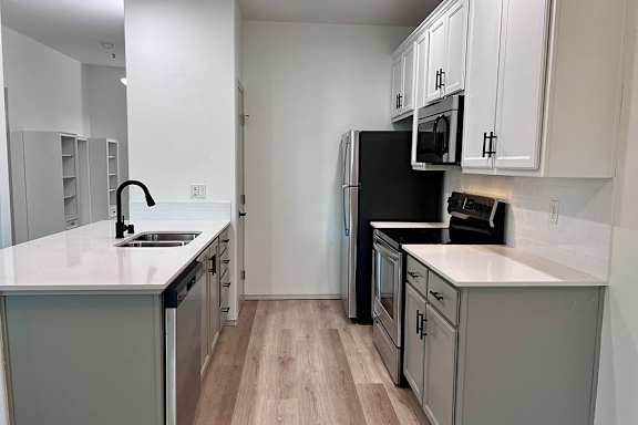 A kitchen with a black fridge and white countertops. at Madison Sierra Sun, Washington, 98374