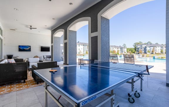 a ping pong table on a patio with a pool at The Parkway on Westlake, Humble