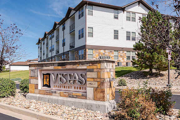 A Vista Apartments building with a stone entrance sign at Vistas at Jackson Creek, Monument, CO