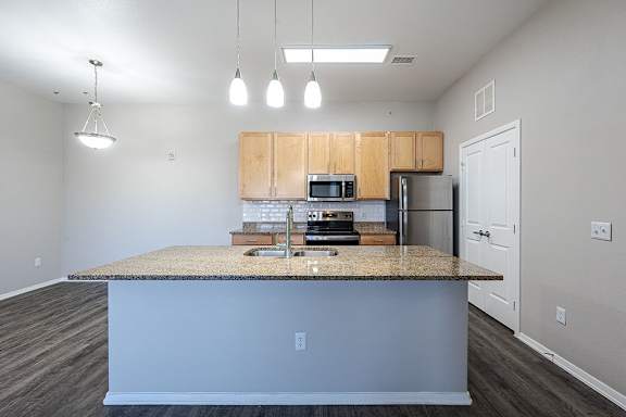 A kitchen with a granite countertop and wooden cabinets at Vistas at Jackson Creek, Monument, CO, 80132