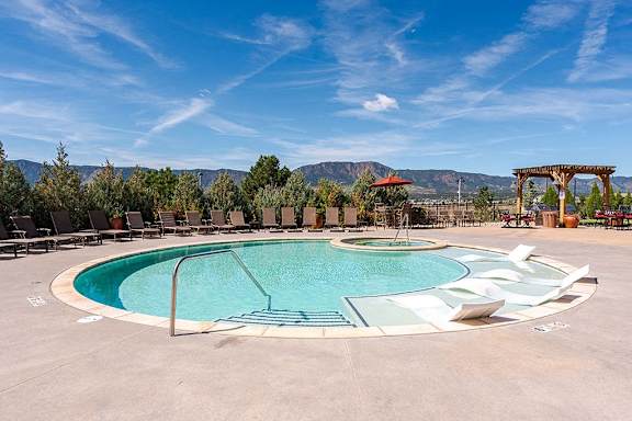 A large outdoor swimming pool surrounded by lounge chairs and trees at Vistas at Jackson Creek, Monument