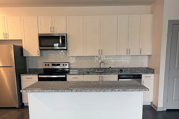 A kitchen with a granite countertop and white cabinets.