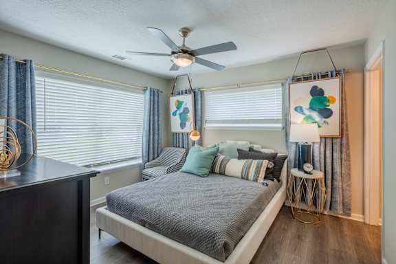 A bedroom with a bed, a ceiling fan, and a window with blinds.