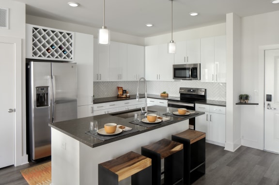 a kitchen with white cabinetry and a large island with a black countertop at Allure on the Parkway in Florida 32746