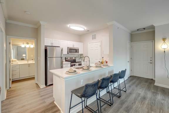 A kitchen with a white counter and black chairs.
