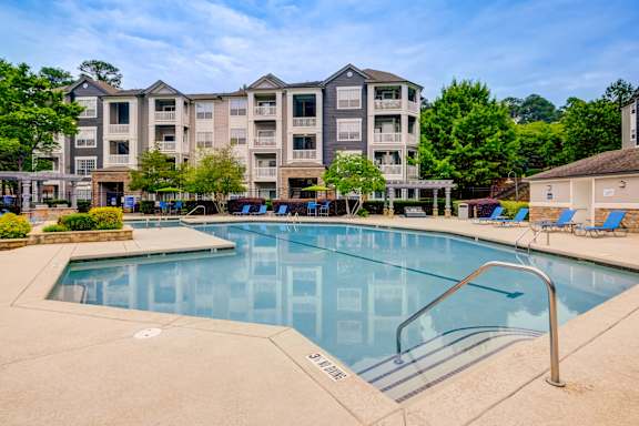 A large swimming pool in front of a multi-story apartment building.