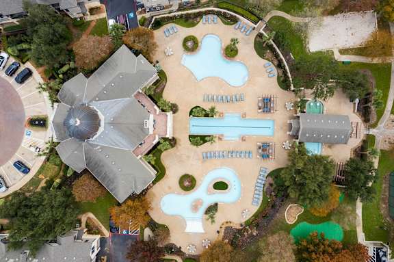 An aerial view of a playground with a slide, swimming pool and a building with a dome.