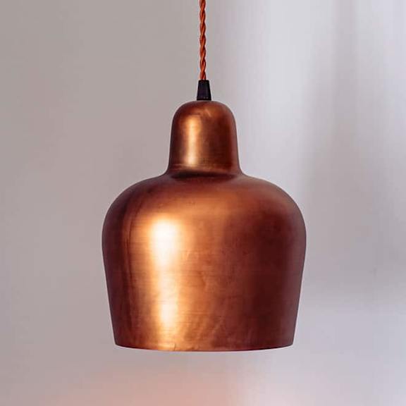 A copper colored pendant light hanging from a brown cord at Folksong Apartments, Flowery Branch, Georgia