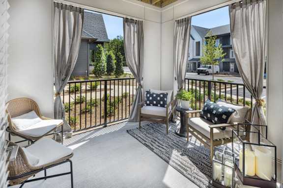 A sunny balcony with a chair, cushion, and a table at Folksong Apartments, Georgia