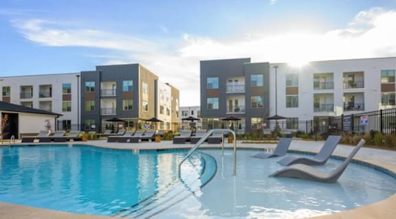 A swimming pool in front of a row of modern apartment buildings.