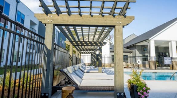 A wooden pergola over a hot tub in a backyard.