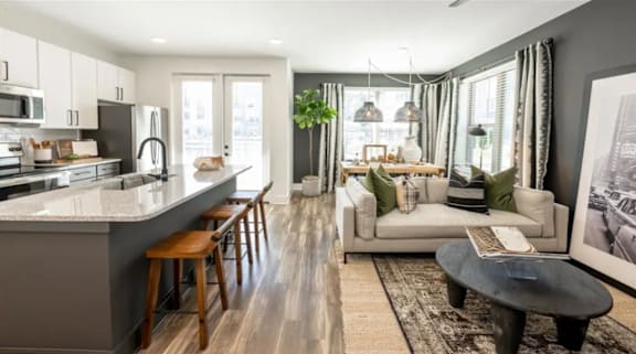 A modern kitchen with a bar stool and a dining area with a couch and a coffee table.