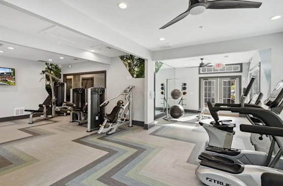 A gym with a variety of equipment including treadmills, weights, and exercise machines at The Hartley at Sweetwater Creek, Duluth 30096
